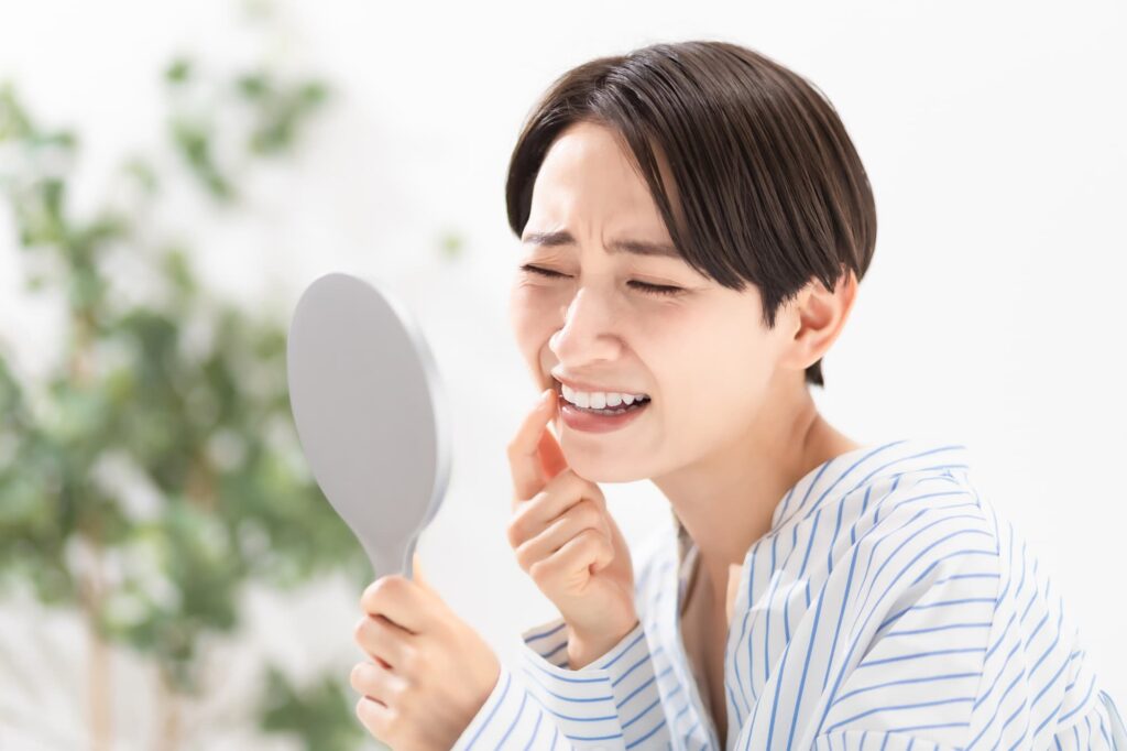 虫歯の初期症状を鏡でセルフチェックする女性