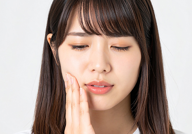 頬に手を当て痛がっている女性