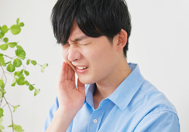 頬に手を当て痛がっている男性