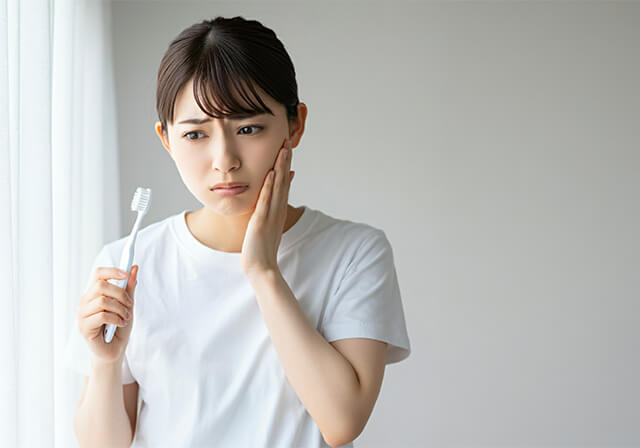 歯磨きで歯に痛みを感じる女性