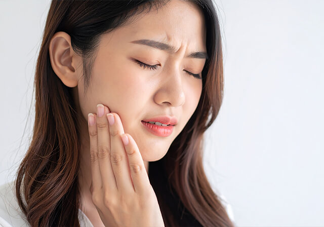 頬に手を当て痛がっている女性